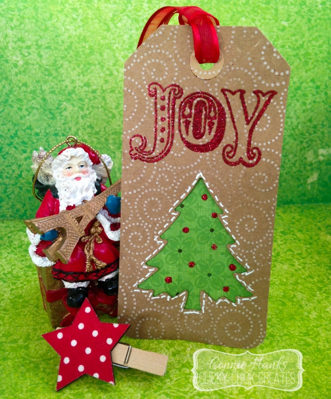 Connie Hanks // ClickyChickCreates.com // Christmas tag on kraft with red tinsel Stampendous Joy, EK Success tree punch, Stickles Christmas Red, Hero Arts Magical Background