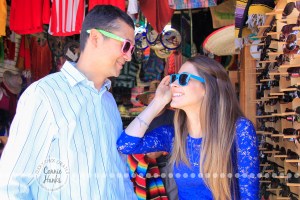 Connie Hanks Photography // ClickyChickCreates.com // engagement couple session, Rosarito, Mexico, mercado, market, colorful, turquoise, blue, gray, wood, wheel, rustic, arches, archways, kiss, sunglasses, hipsters
