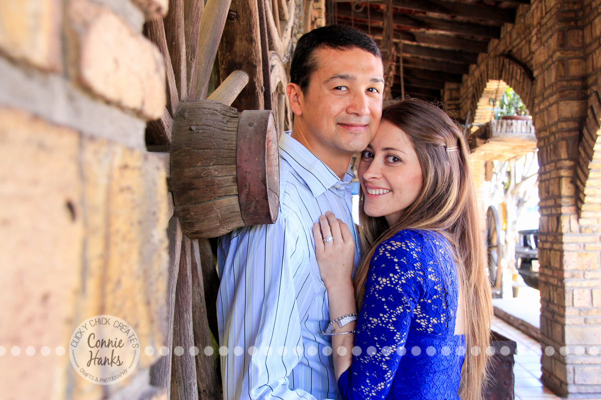 Connie Hanks Photography // ClickyChickCreates.com // engagement couple session, Rosarito, Mexico, mercado, market, colorful, blue, gray, wood, wheel, rustic, arches, archways, kiss