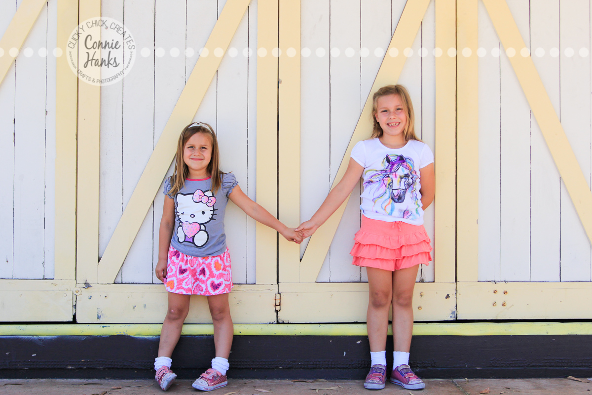 Connie Hanks Photography // ClickyChickCreates.com // Sisters holding hands, photos in front of yellow and cream barn doors